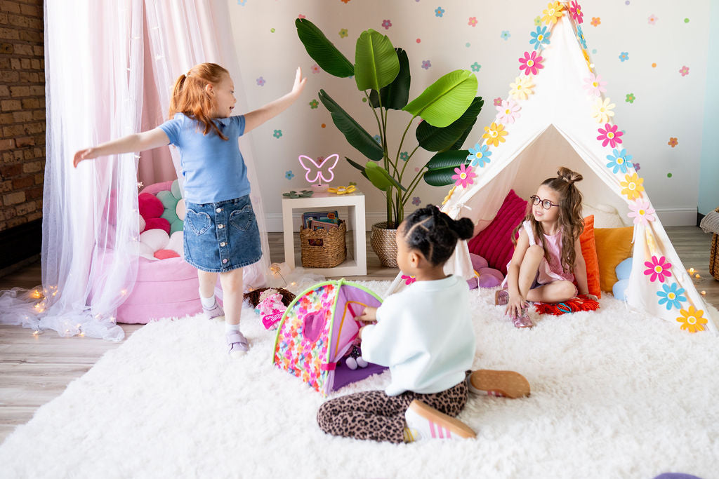 Three first grade age girls playing with soft dolls and accessories in a girl's playroom scene
