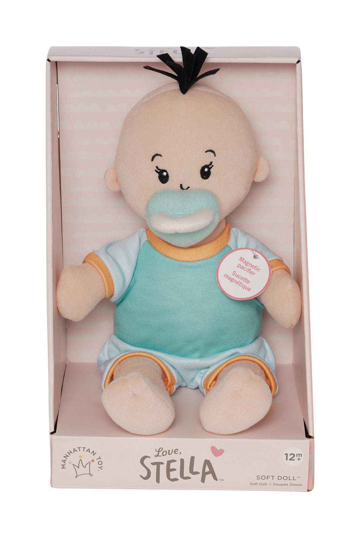 soft baby doll with peach skin and black hair wearing a onesie with short sleeves and pants with a magnetic pacifier in open front box packaging
