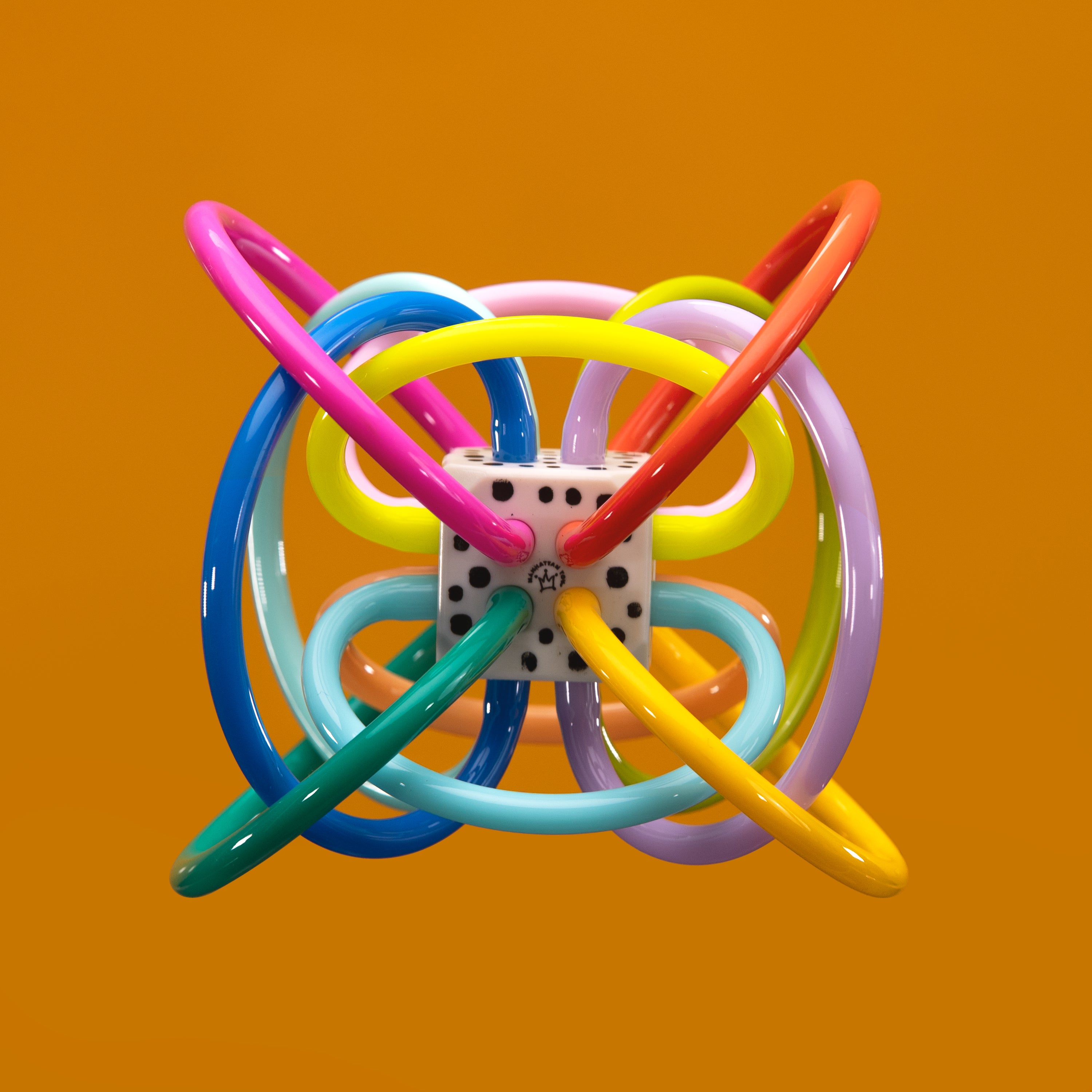 colorful loop ball toy on an orange background.