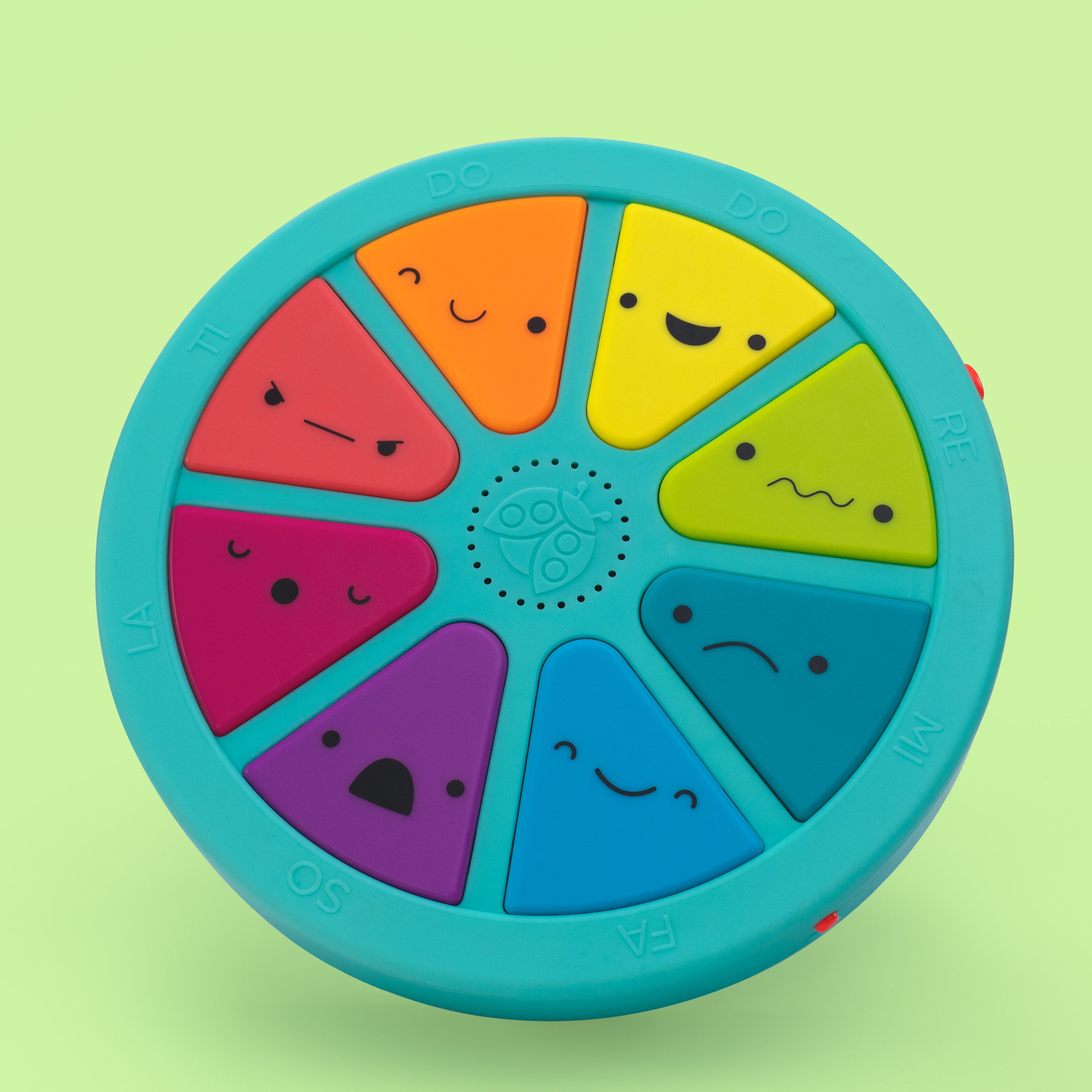 Colorful circular toy with smiling faces on a green background
