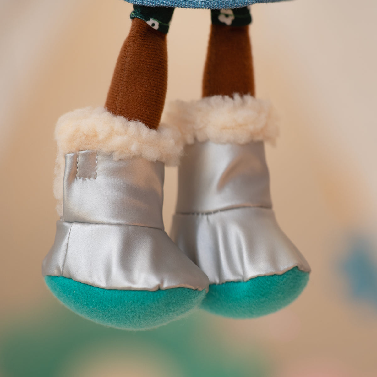 Close up of a soft doll wearing silver and blue fuzzy boots