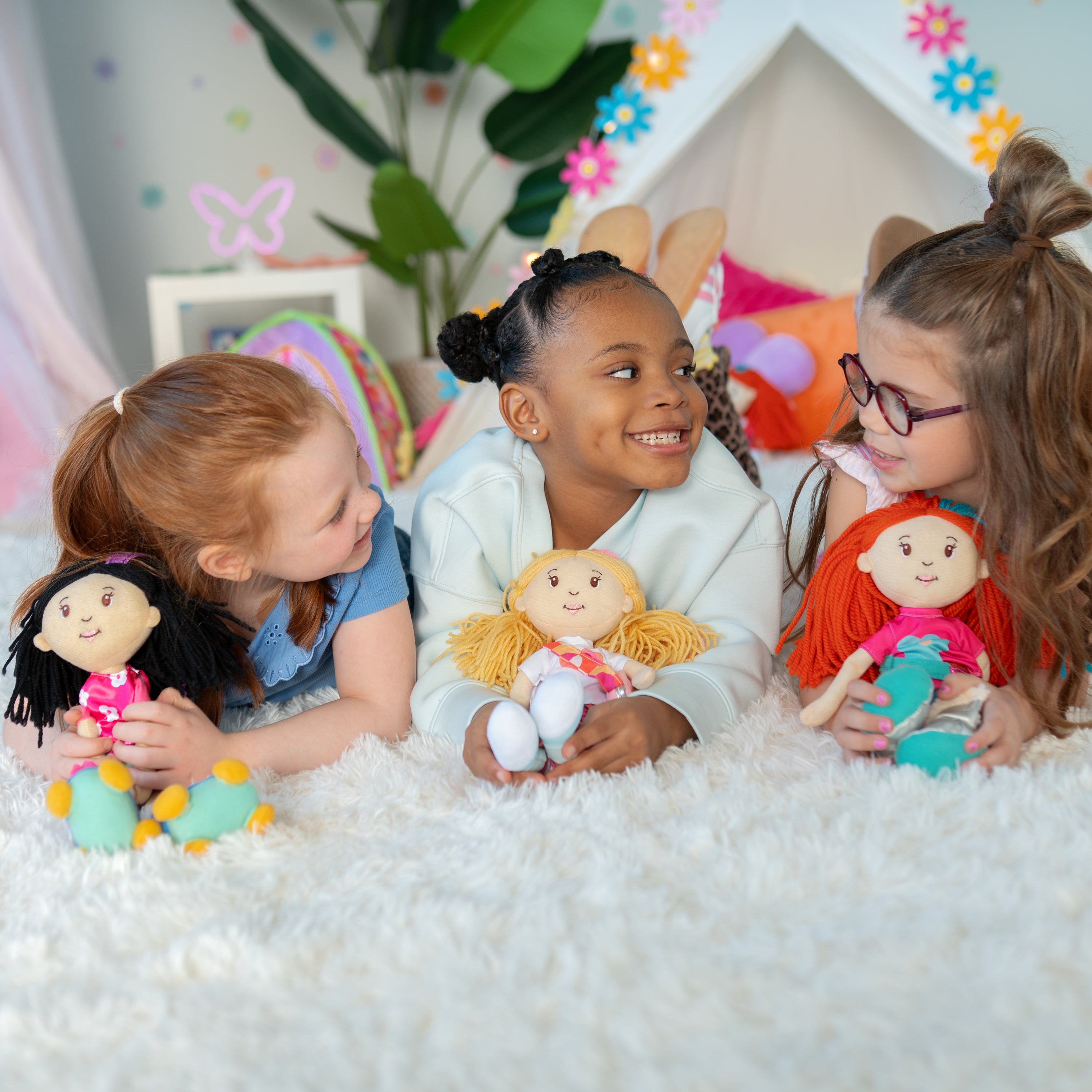3 girls laying on the floor, playing with Groovy Girls dolls