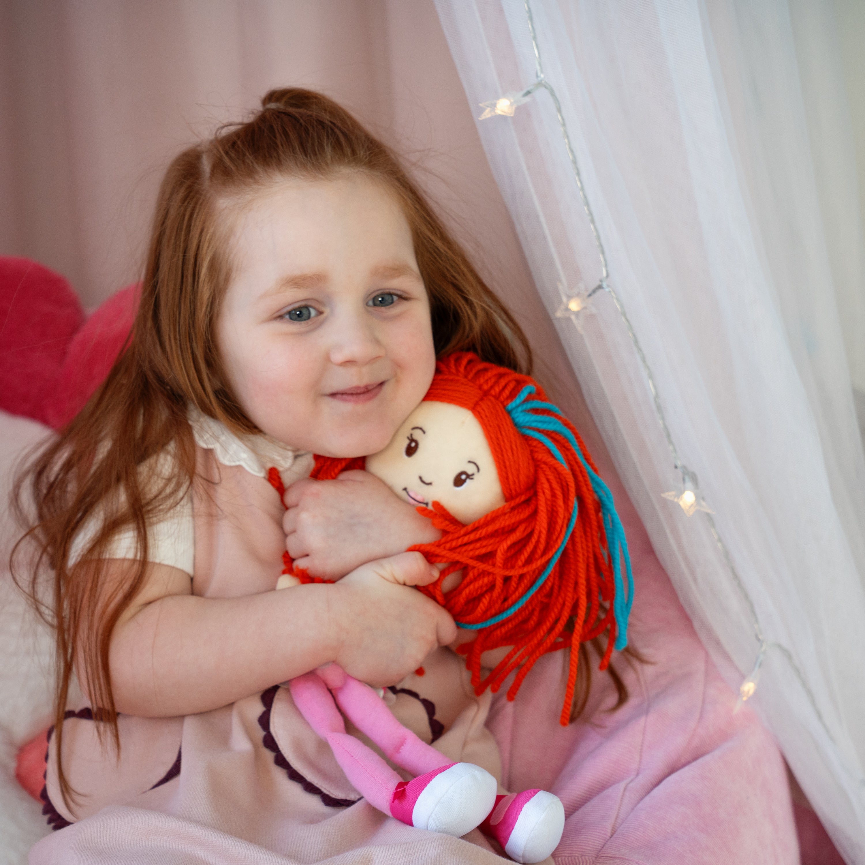 Girl hugging Groovy Girls Poppy doll, smiling