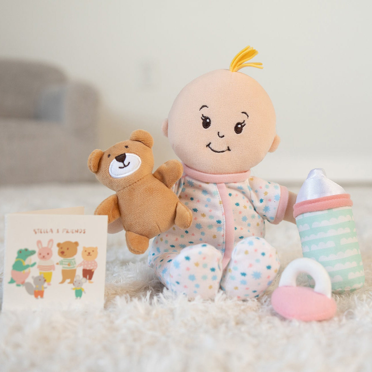 baby doll toy in pajamas with a teddy bear, a book a pacifier, and a bottle.