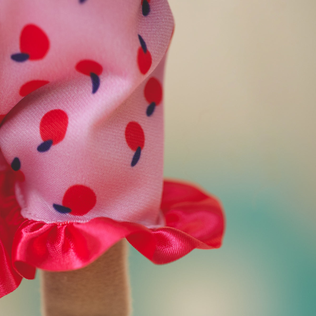 close up of doll wearing pink pajama shorts with a cherry pattern and red, frilly edges
