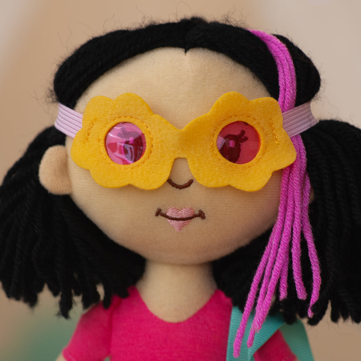 close up of a soft doll wearing yellow flower sunglasses