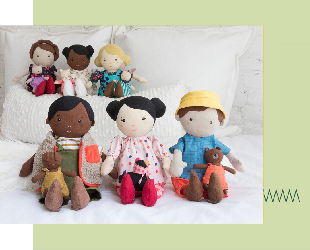6 dolls of different ethnicities and outfits sitting on a child's bed