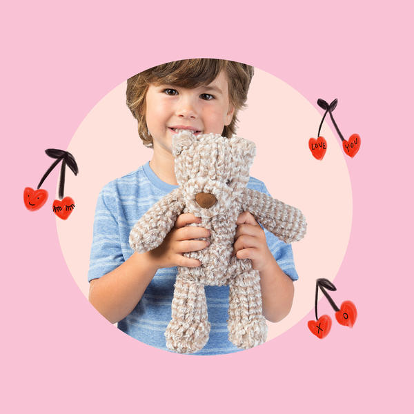 Caucasian boy holding a beige teddy bear with floating heart cherries in background