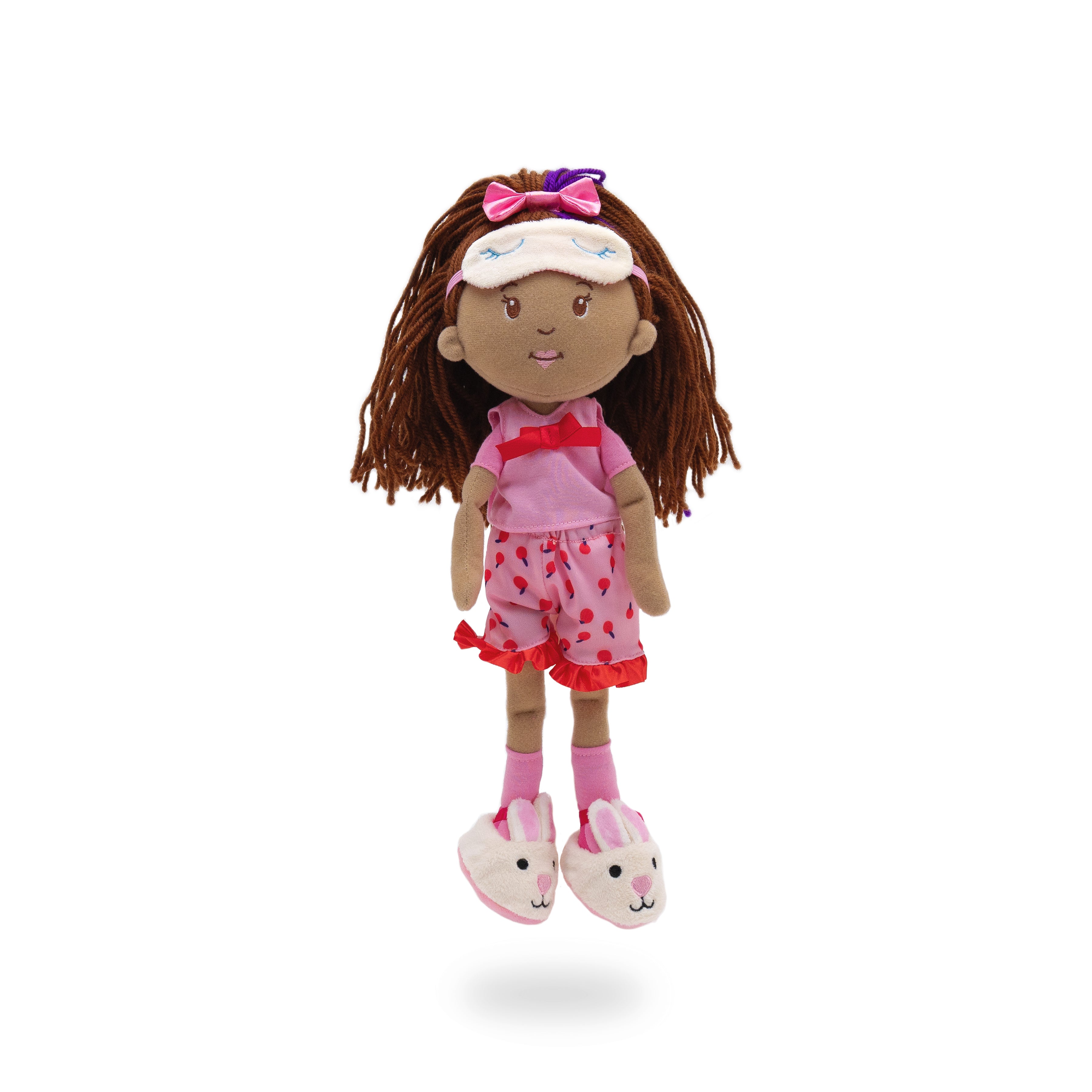 Soft doll wearing pink pajama set with cherry pattern shorts, bunny slippers, and sleep mask.
