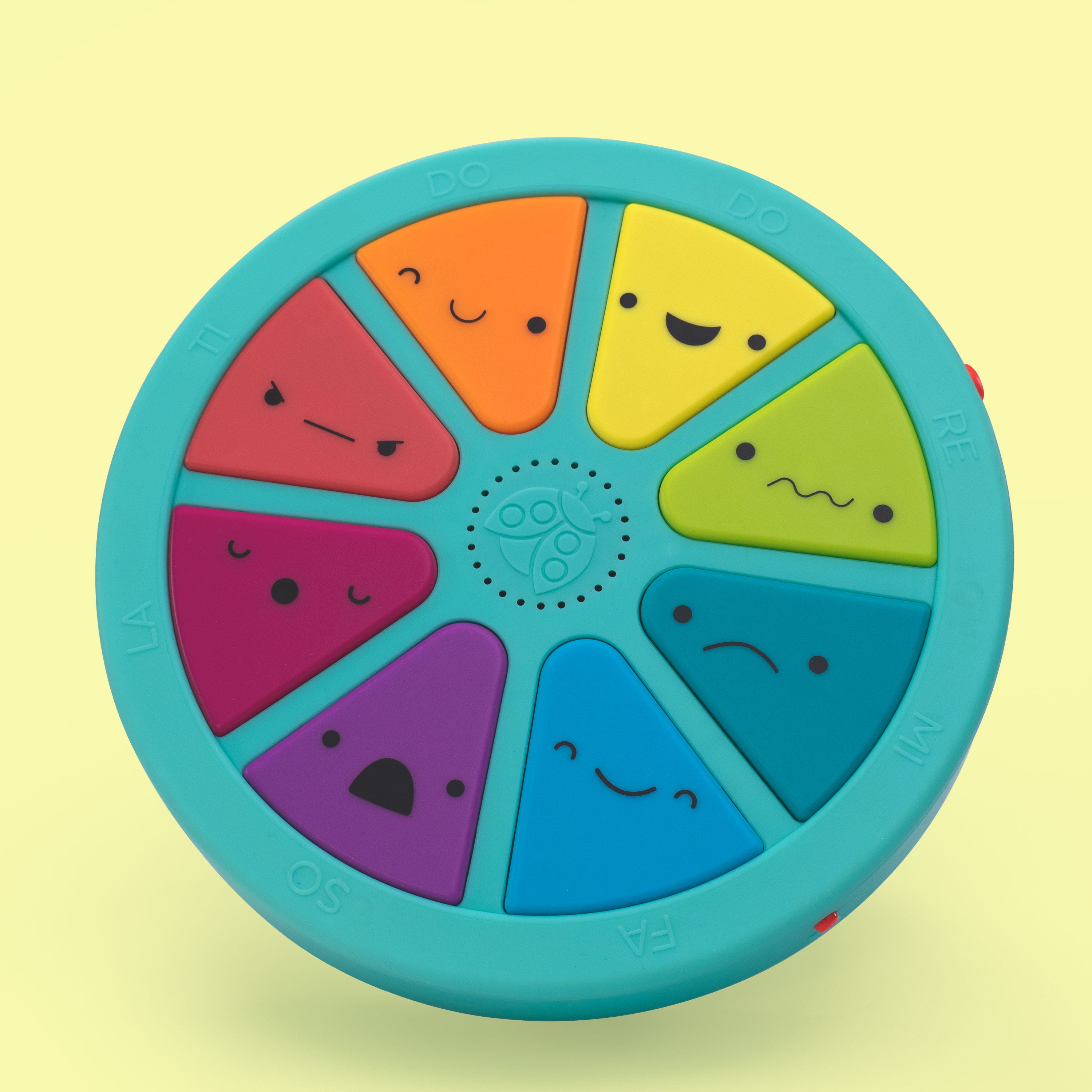 Colorful circular toy with smiling faces on a yellow background
