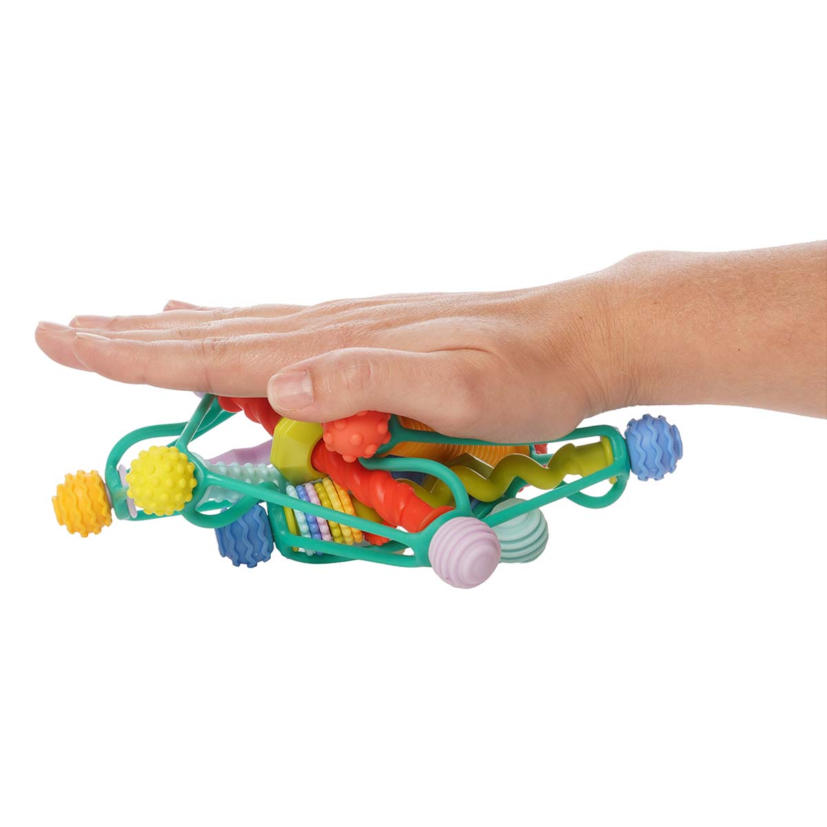 A hand pushes down on the colorful Whirzle infant toy, squishing it to show its flexibility.