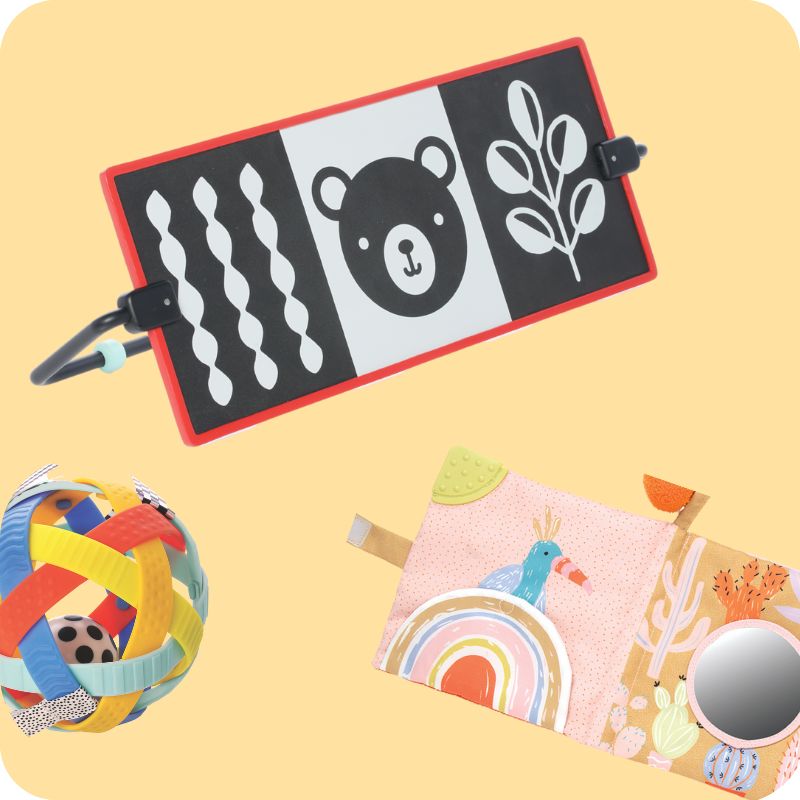 A sensory ball, black and white tummy time toy and soft baby book on a light tan background