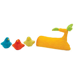 Three plush toy birds, blue, red, and green, next to a plush toy tree branch that is orange with green leaves.