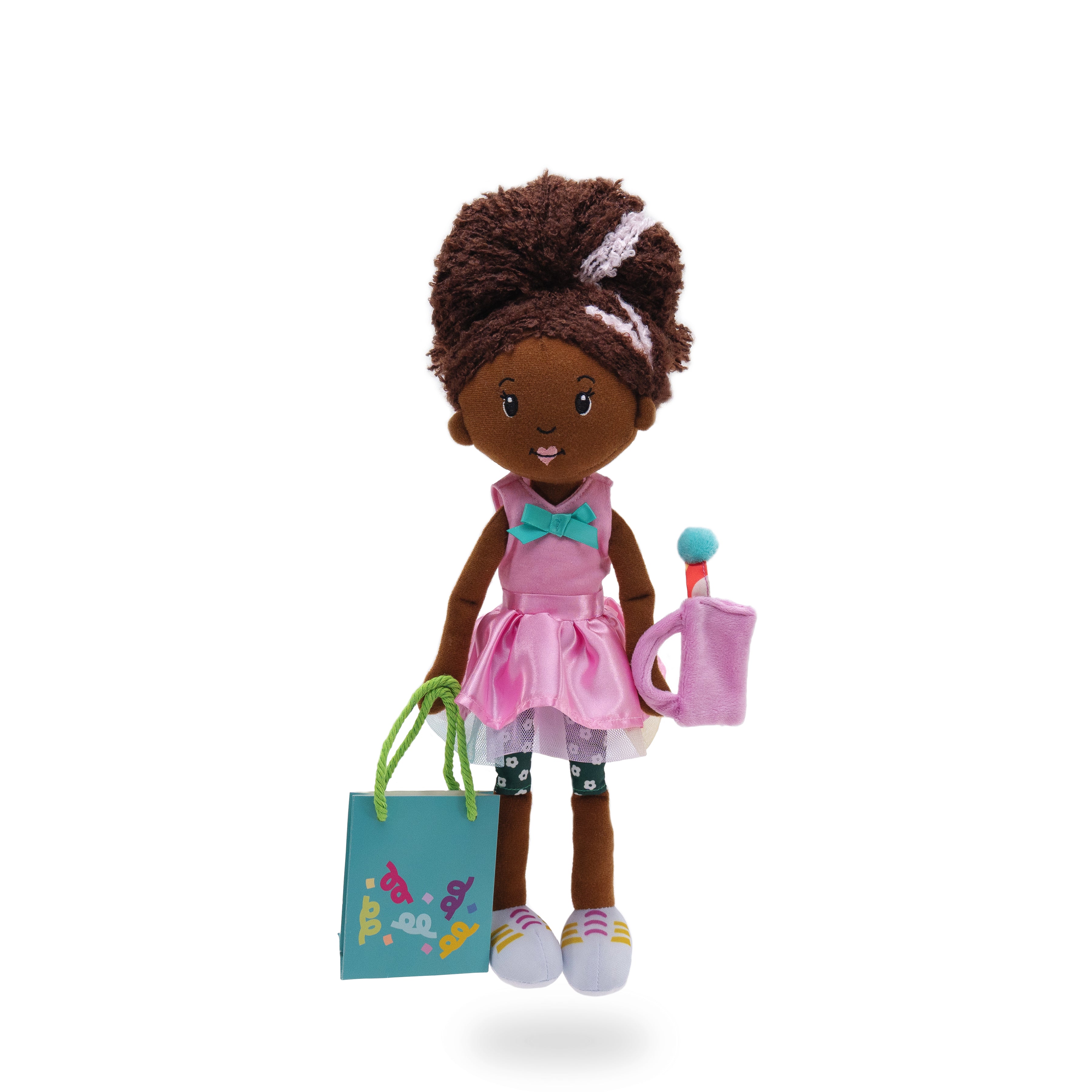 Soft doll wearing pink shirt with blue bow, pink skirt, holding a cloth purse and paper gift bag.