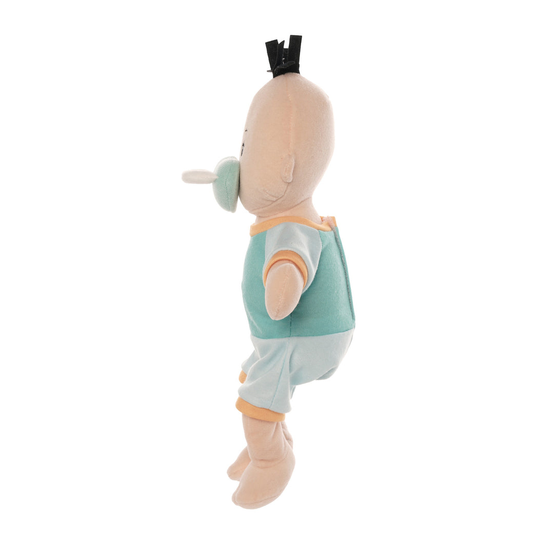 soft baby doll with peach skin and black hair tuft in a short sleeve and shorts outfit seated with a blue magnetic pacifier attached to the face