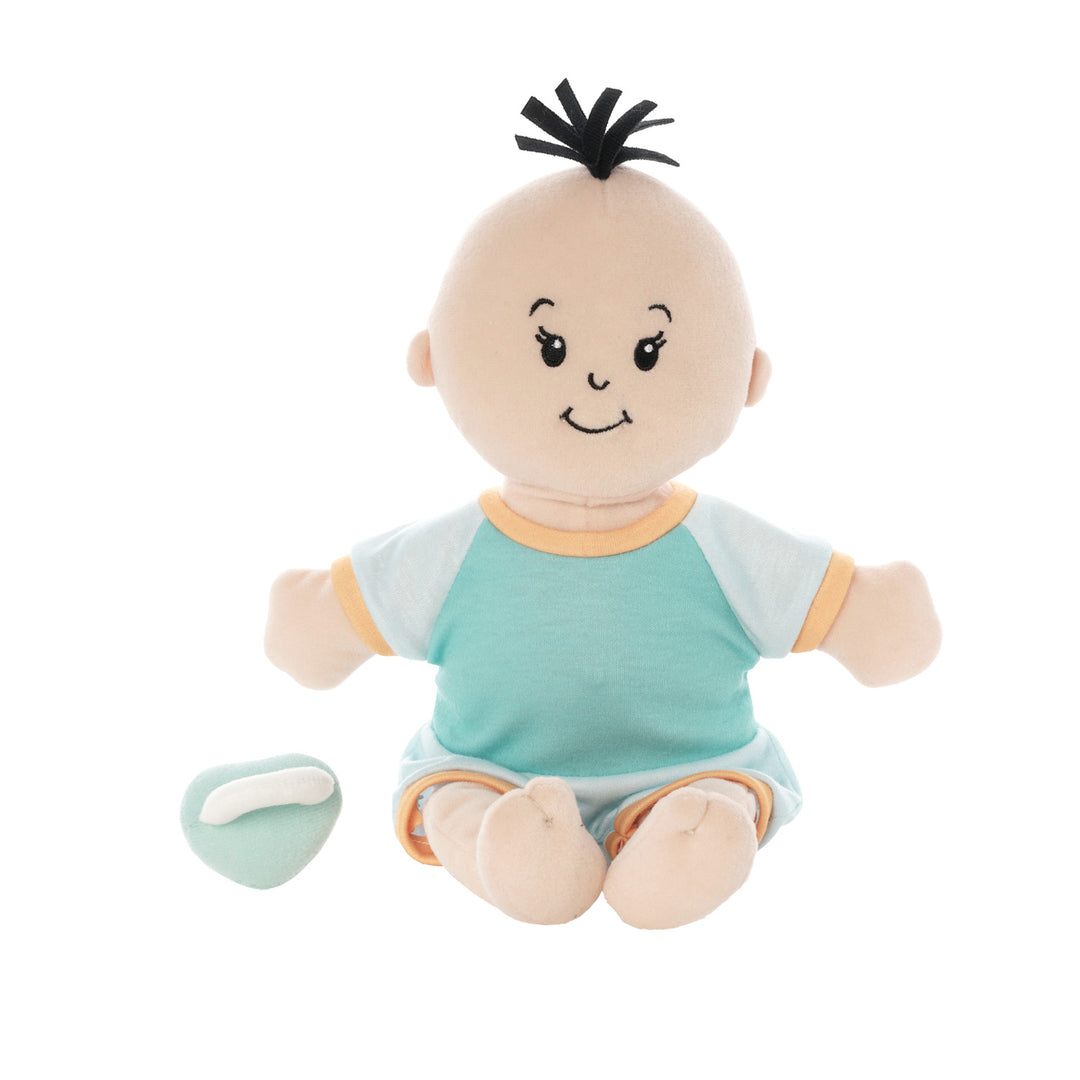 soft baby doll with peach skin and black hair tuft in a short sleeve and shorts outfit seated with a blue magnetic pacifier off to the side