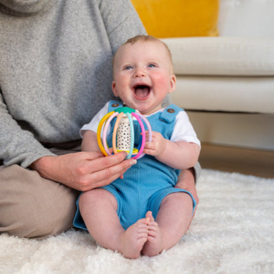 happy baby playing with a colorful toy ball