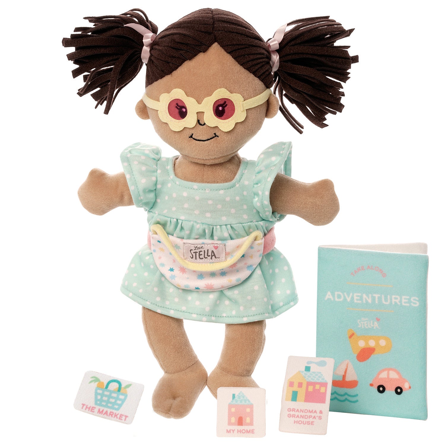 Wee Baby Stella doll wearing glasses and a dress, with a toy adventure book and location cards.