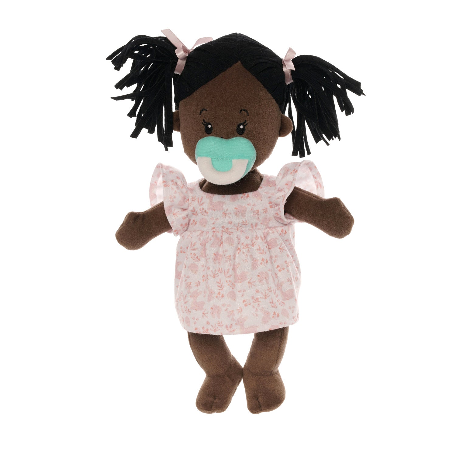 brown skinned soft baby doll with black pigtails in a pink dress with a blue magnetic pacifier attached to the doll's face