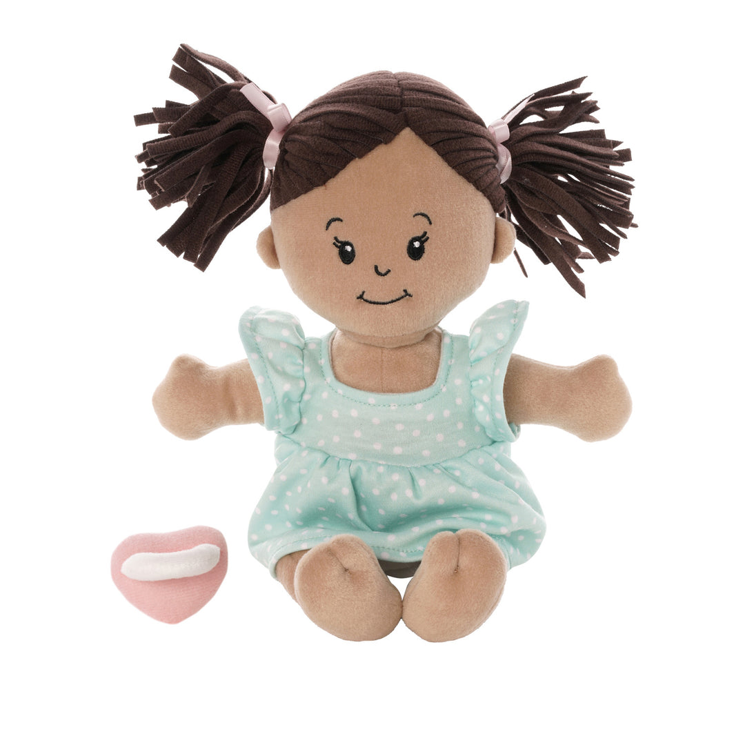 seated beige soft baby doll with brown pigtails in blue dress seated with pink magnetic pacifier off to the side