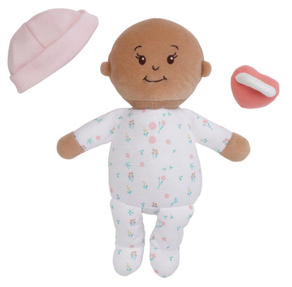 beige skinned soft baby doll with removable pink beanie and pink magnetic pacifier off to side of doll