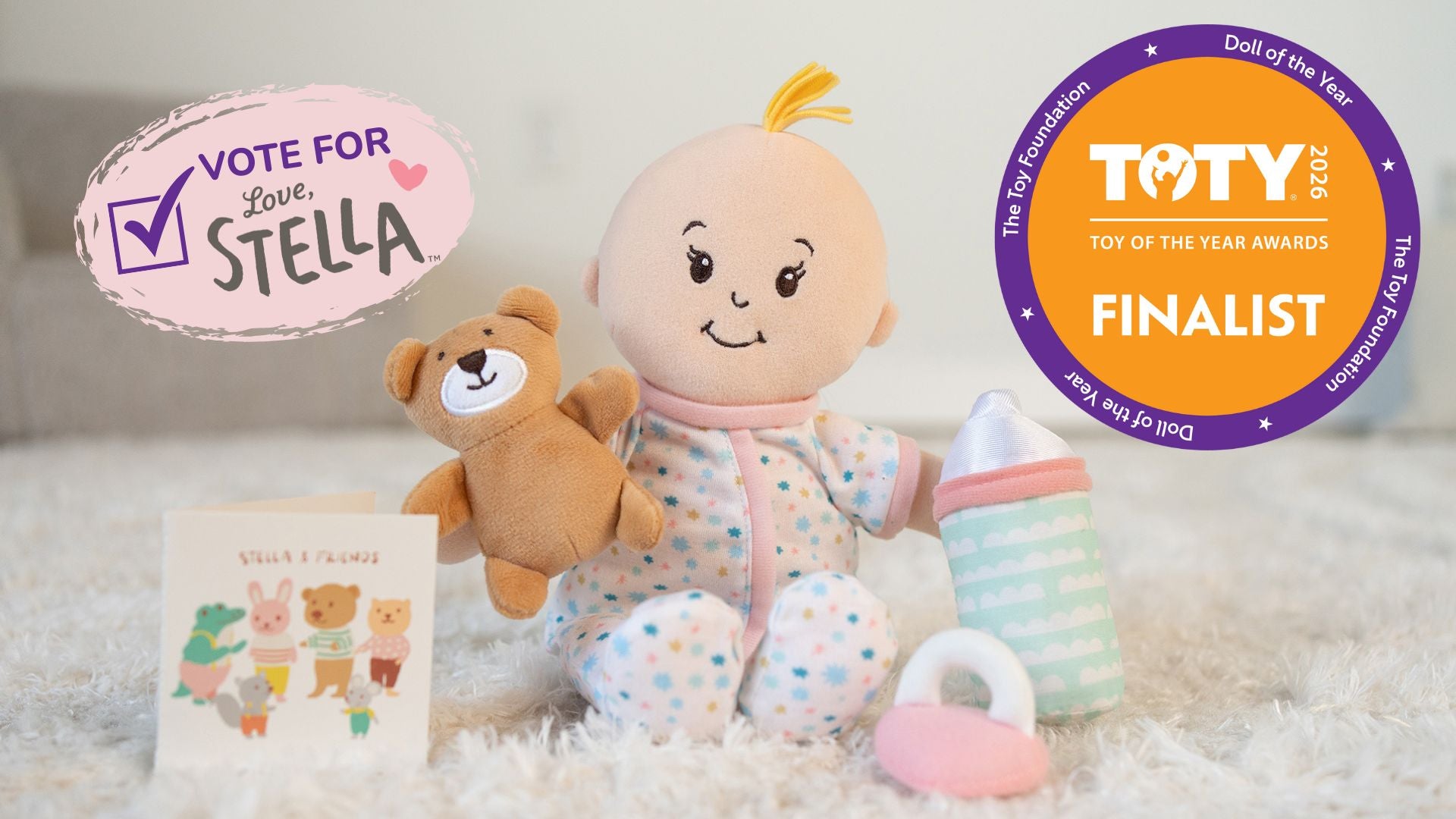 Baby doll with teddy bear, book, and pacifier with 'Vote for Stella' and 'Toy of the Year Awards' finalists badge.