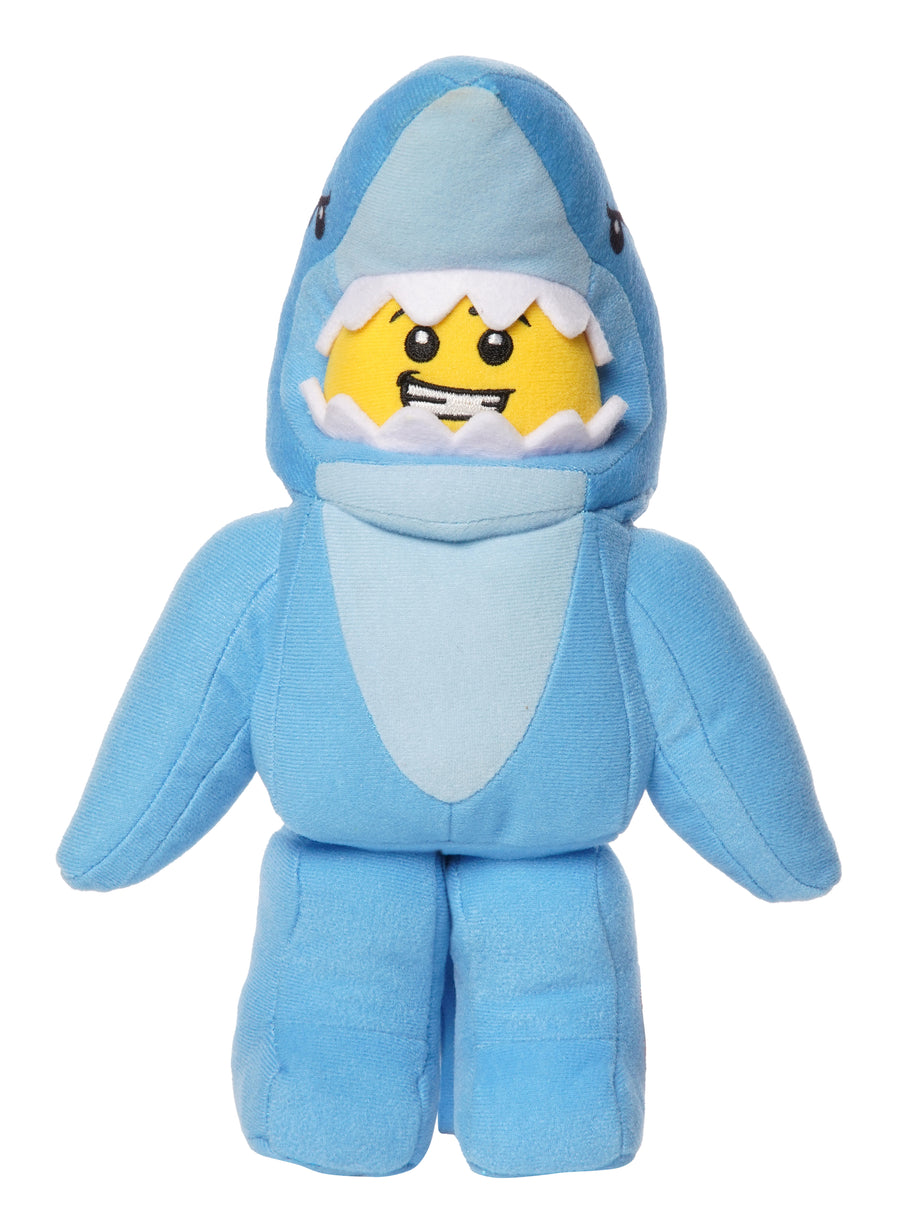 Light blue shark costume plush inspired by LEGO shown in a full front view with a grinning yellow face framed by soft white teeth.