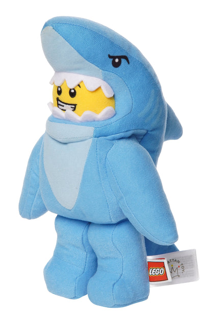 Light blue shark costume plush inspired by LEGO shown in three quarter view with a grinning yellow face inside the shark hood.