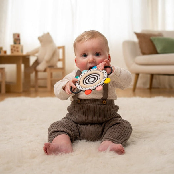 Little baby boy teething on colorful polka dot toy