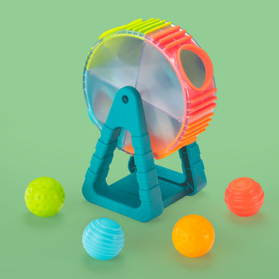 Colorful toy ball launcher with four textured balls in green, blue, orange, and red, displayed against a light green background.