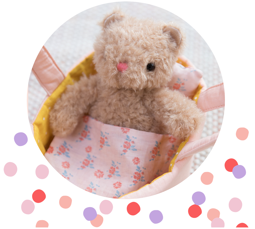 Bea Bear plush toy sitting in doll carrier