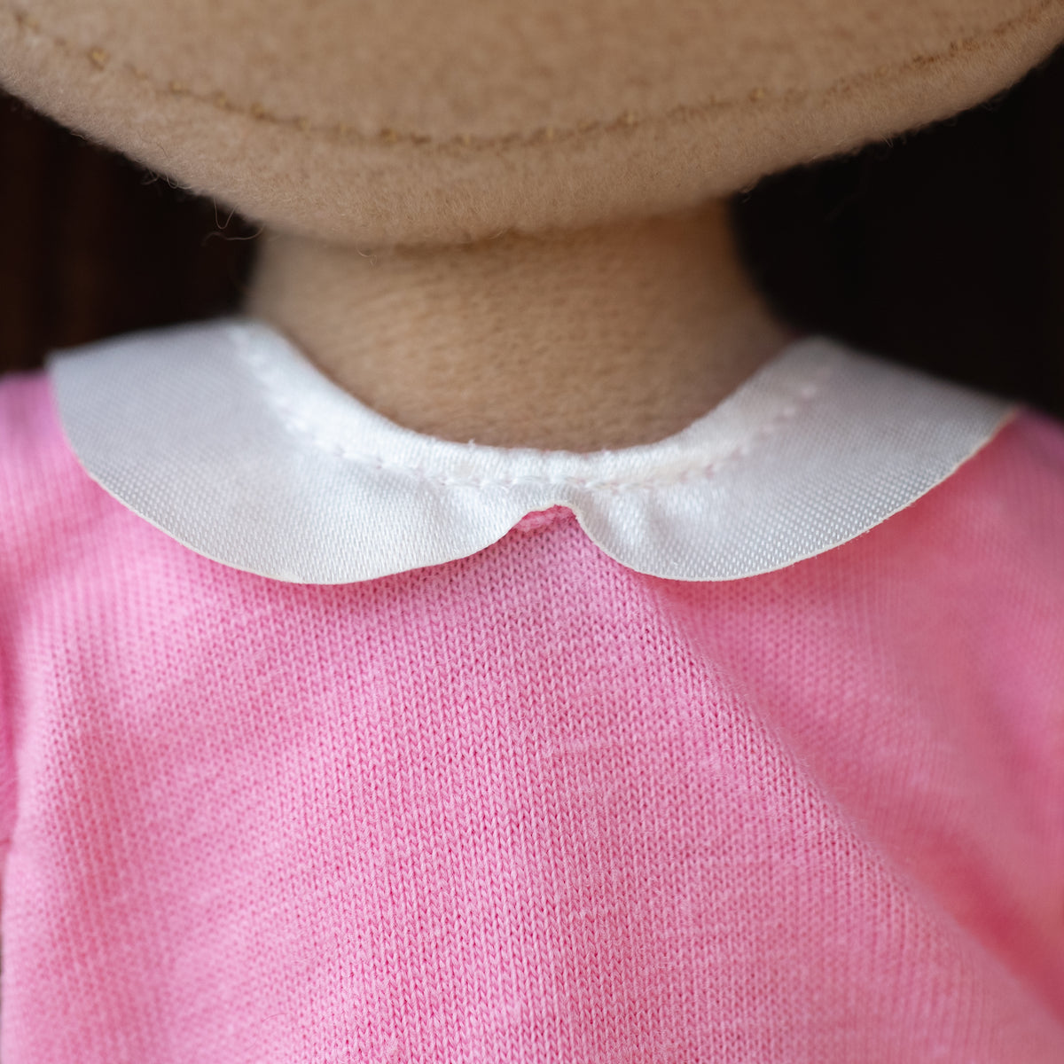 close up of a soft doll wearing a pink shirt with a white collar