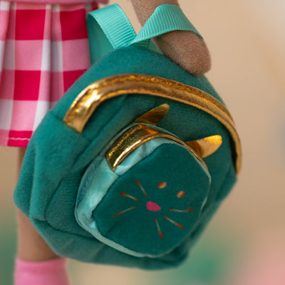close up of a soft doll holding a teal backpack with gold zippers and a kitty face and ears in the front