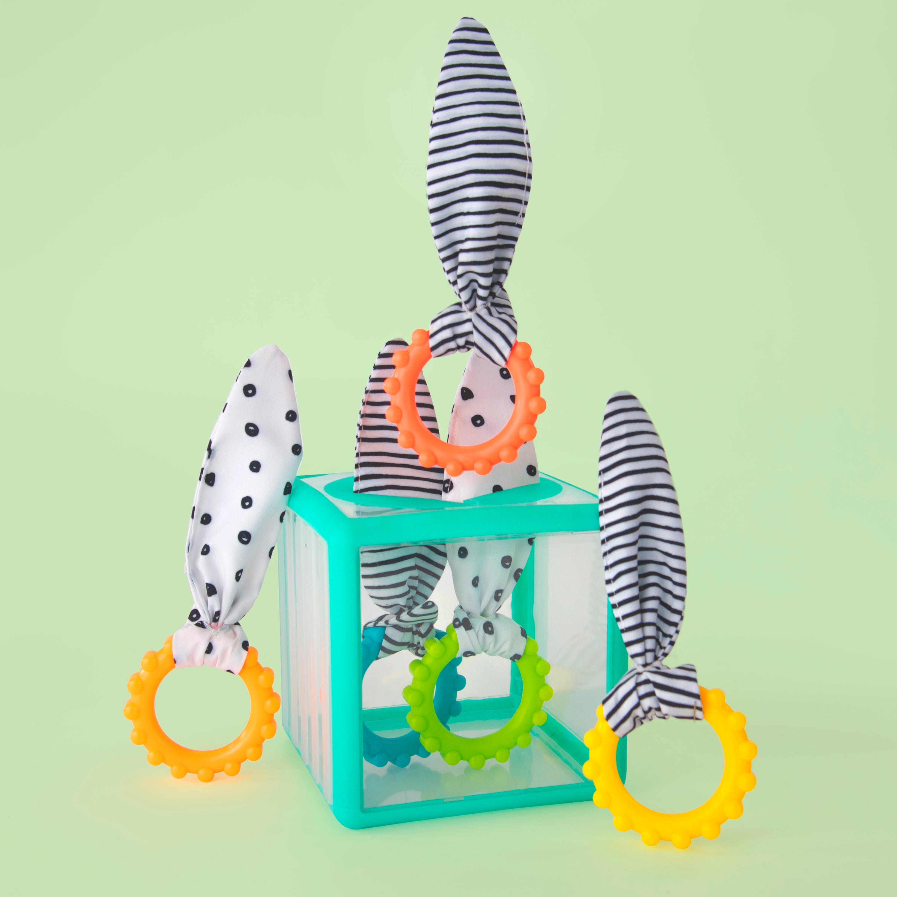 Baby teething toy set with colorful rings and a striped toy on a light green background