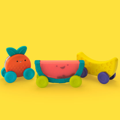 Three colorful fruit-shaped toys on wheels against a yellow background