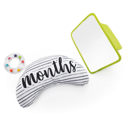 Striped bolster pillow with 'months' text, colorful ring, and green mirror on a white background