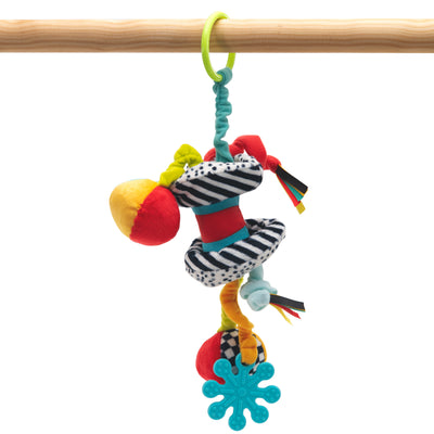 Colorful baby toy with various textures and patterns hanging from a wooden bar on a white background.