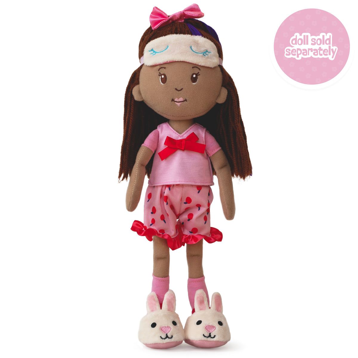 soft doll wearing pink pajama set with cherry pattern shorts, bunny slippers, and sleep mask on her head.