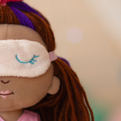 close up of doll wearing a sleeping mask over her eyes