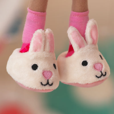 close up of soft doll wearing white bunny slippers