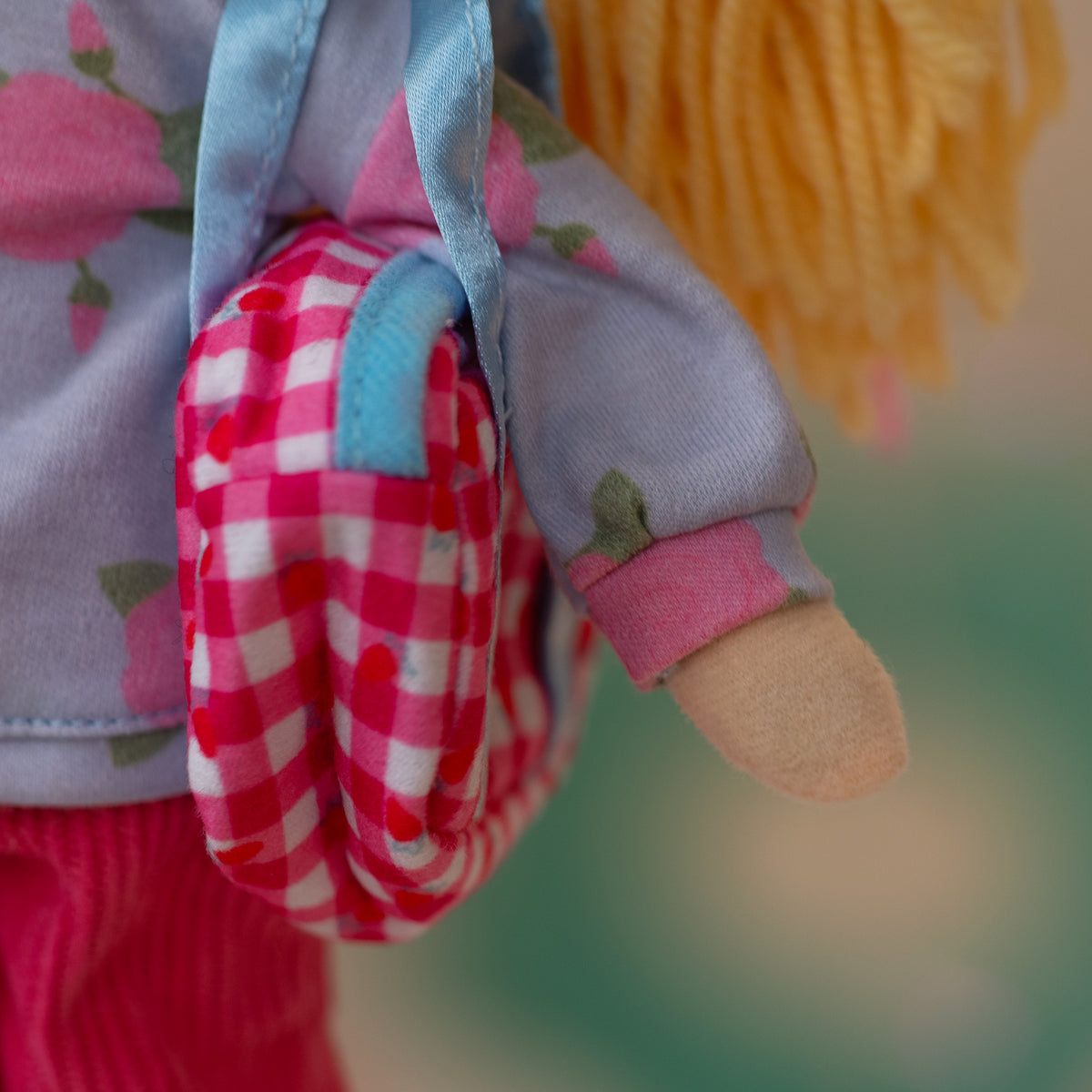 close up of doll holding pink duffel bag