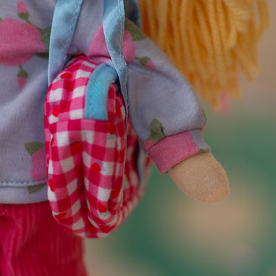 close up of doll holding pink duffel bag