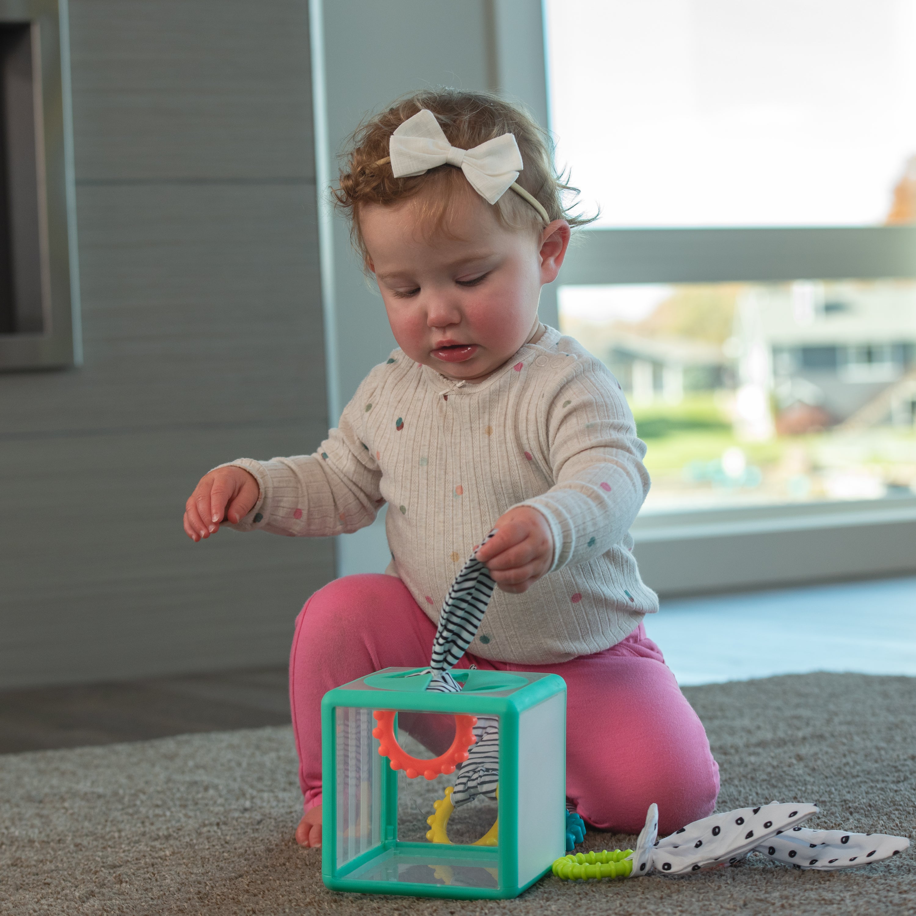Child playing with a colorful toy on the floor near a window