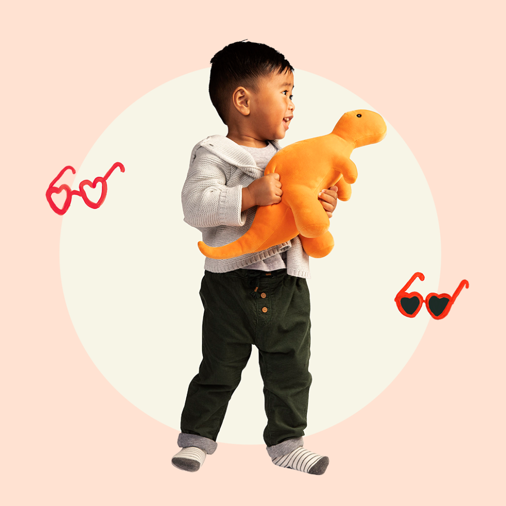 Asian toddler boy holding orange dinosaur, with floating heart shaped glasses around him