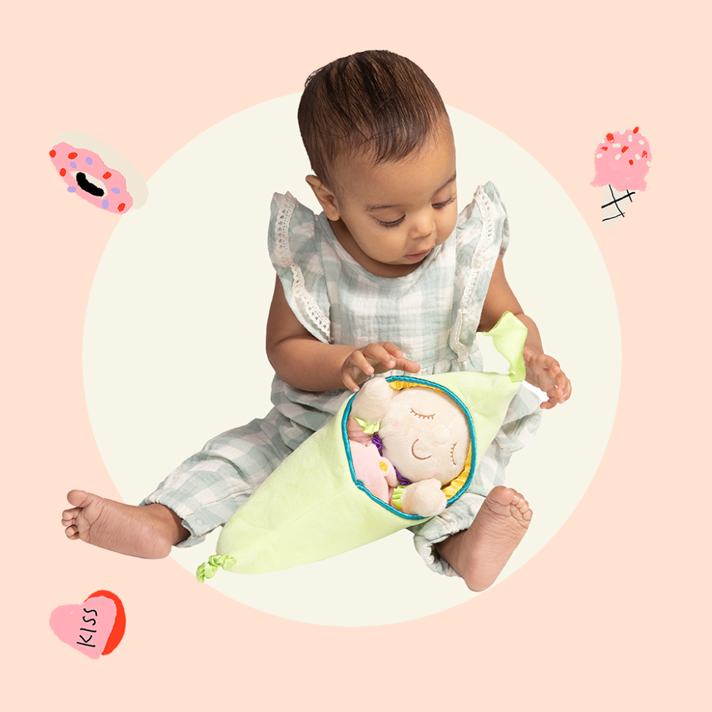 Baby girl holding Snuggle Pods plush toy on natural background with floating hearts and donuts