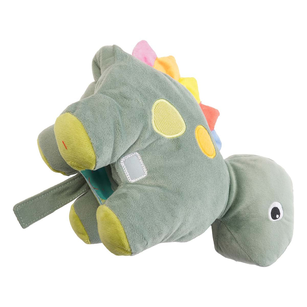 Angled view of a plush green dinosaur with colorful spikes and spots. A velcro loop on the tummy is undone. 