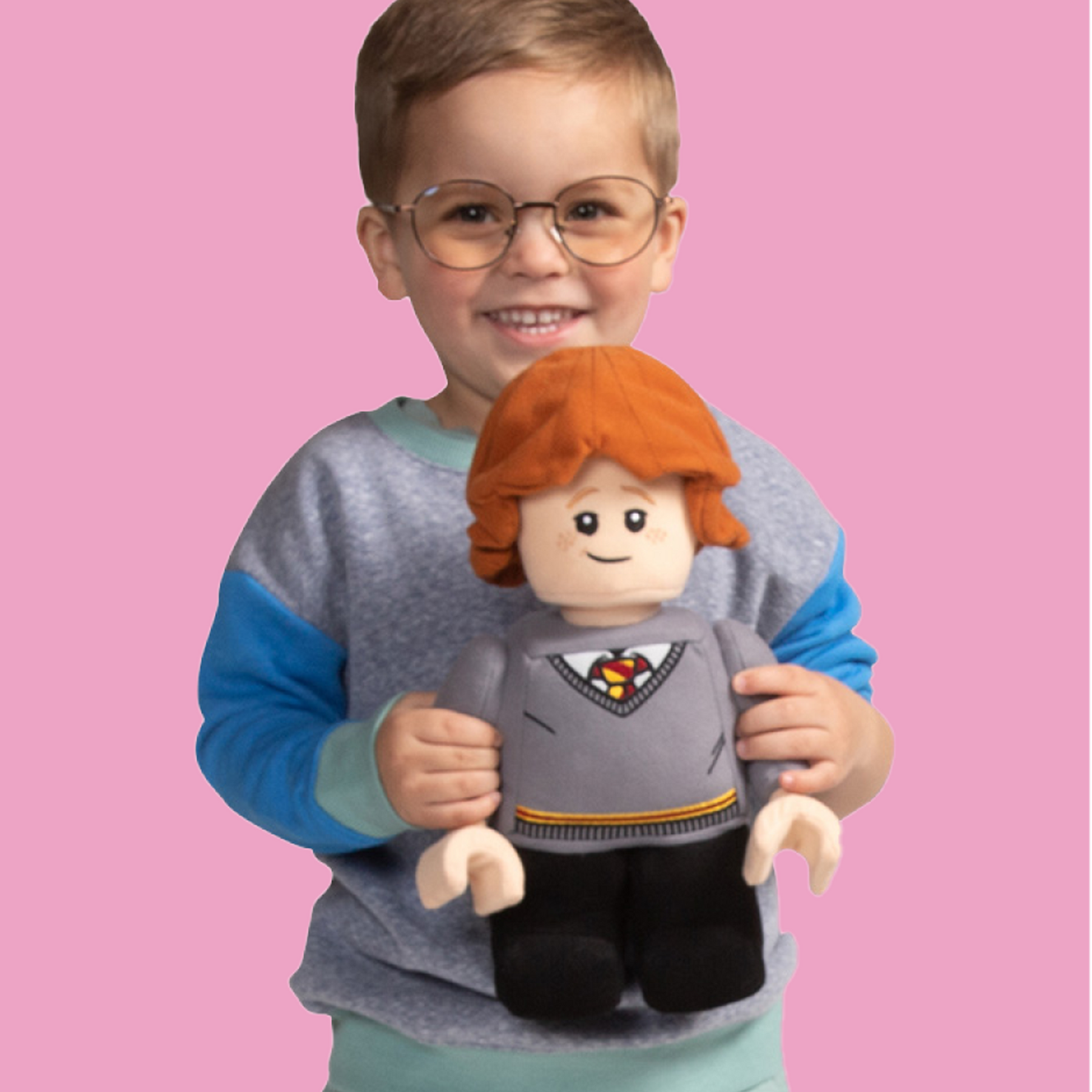 Boy in glasses playing with Hermione plush character doll
