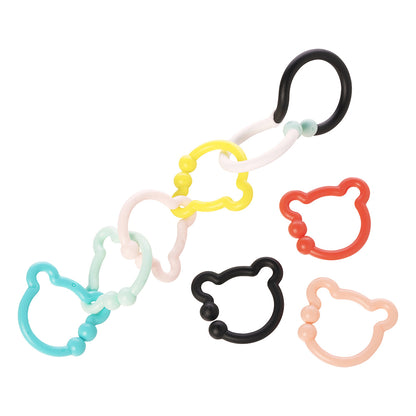 A black and white S-shaped hook connected to 4 colorful bear-shaped rings while 3 rings lay to the side.