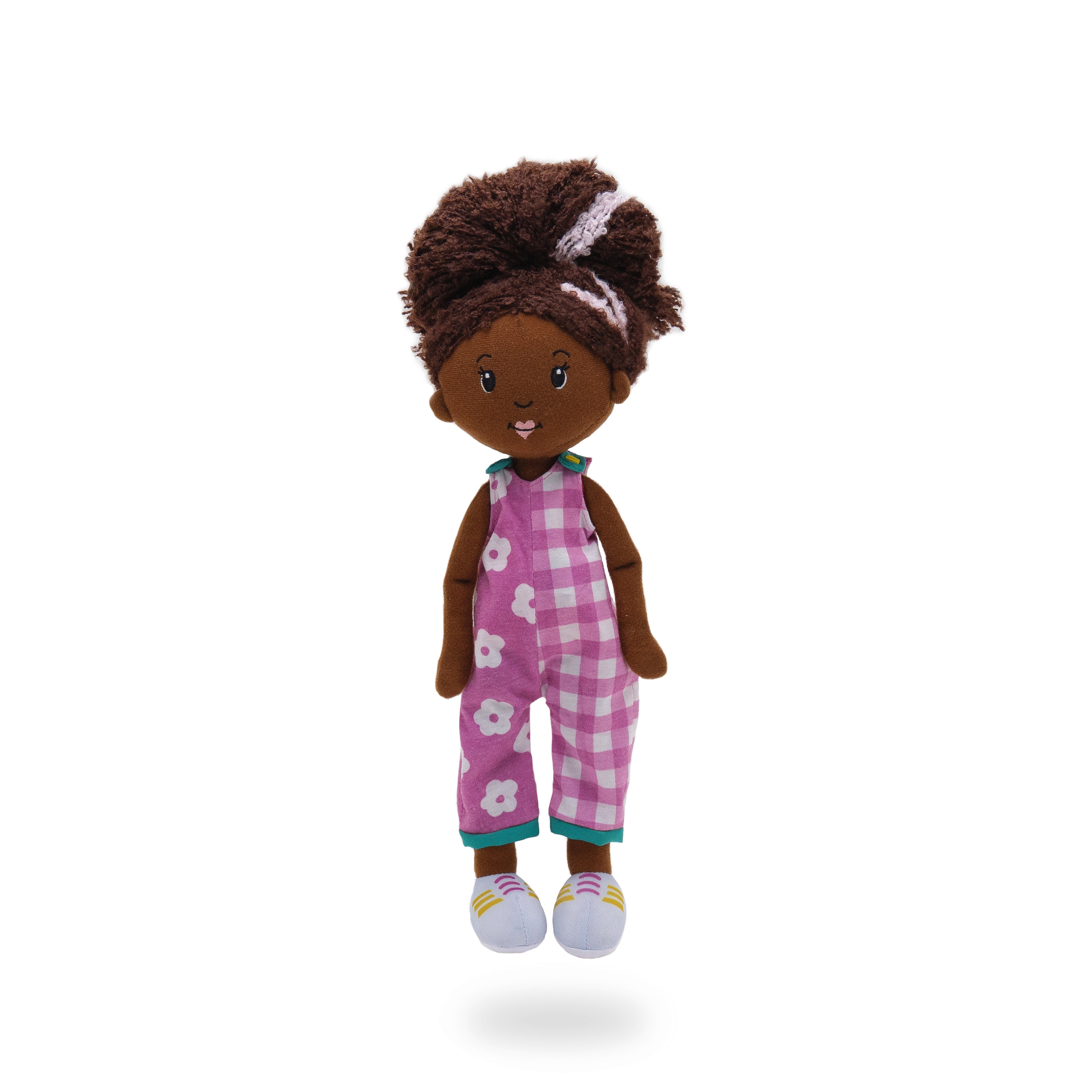 Soft doll wearing purple and white overalls with floral pattern on one side and gingham pattern on the other. 