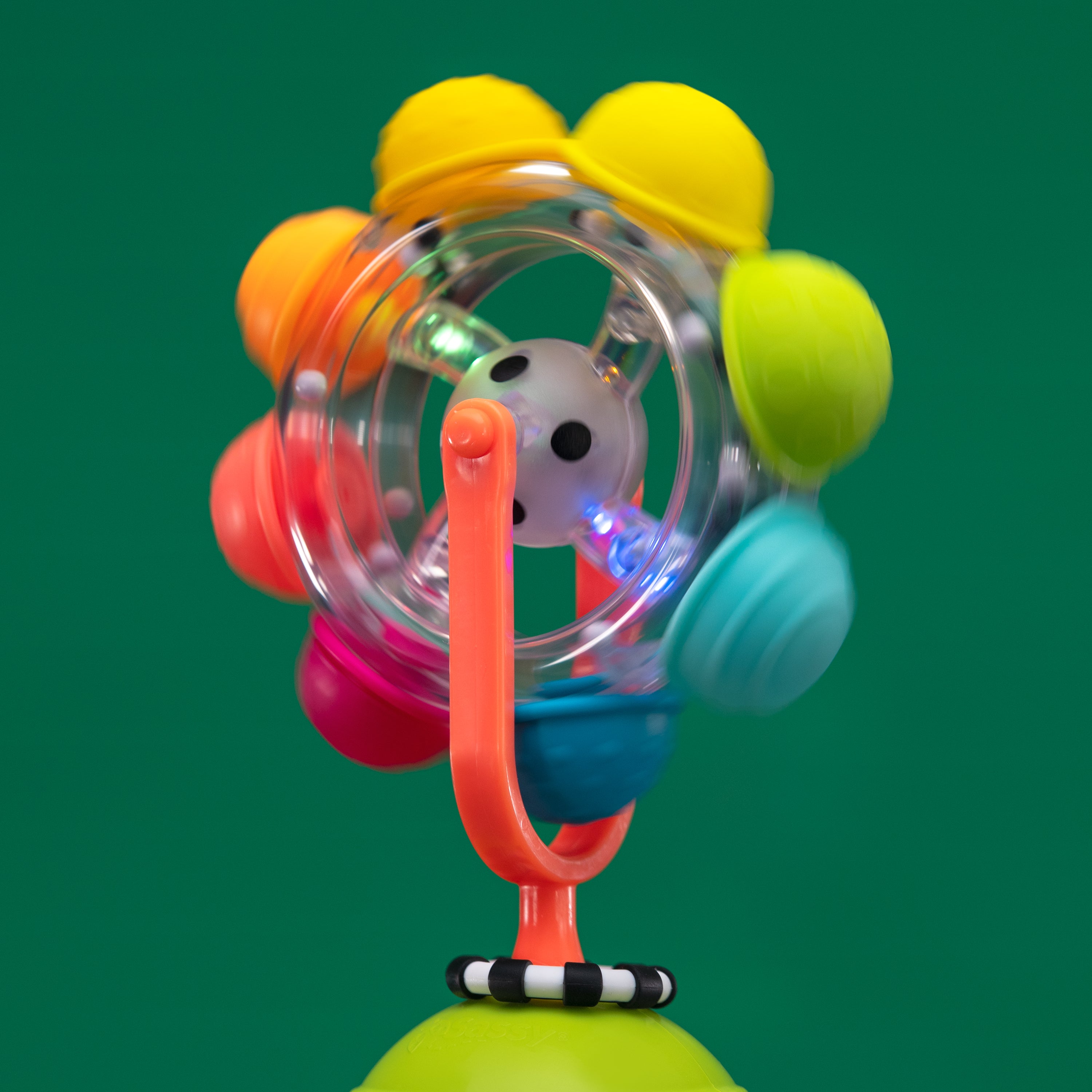 rainbow reel tray toy spinning, and lighting up green and blue, on a green background.